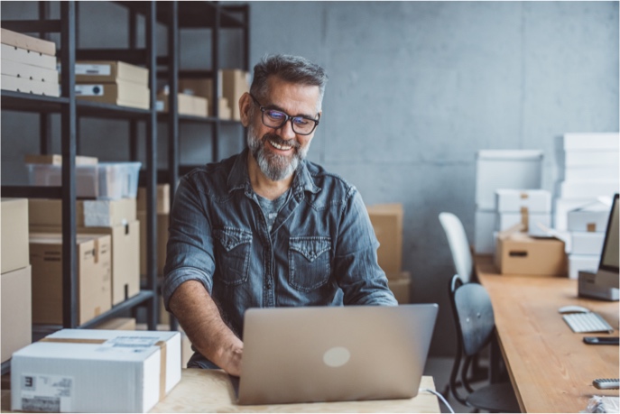 Merchant on a laptop preparing to ship a package.