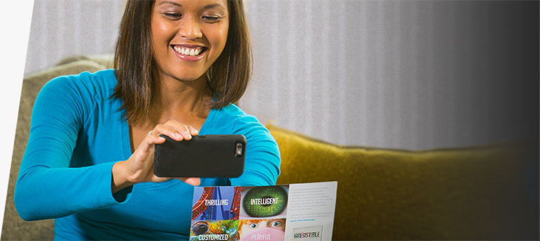 Woman scanning QR code on a mail advertising postcard.